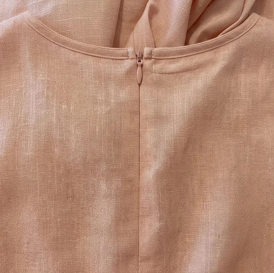Detailed close-up of the soft pink linen-viscose fabric texture with the zipper and matching belt of the maxi dress.