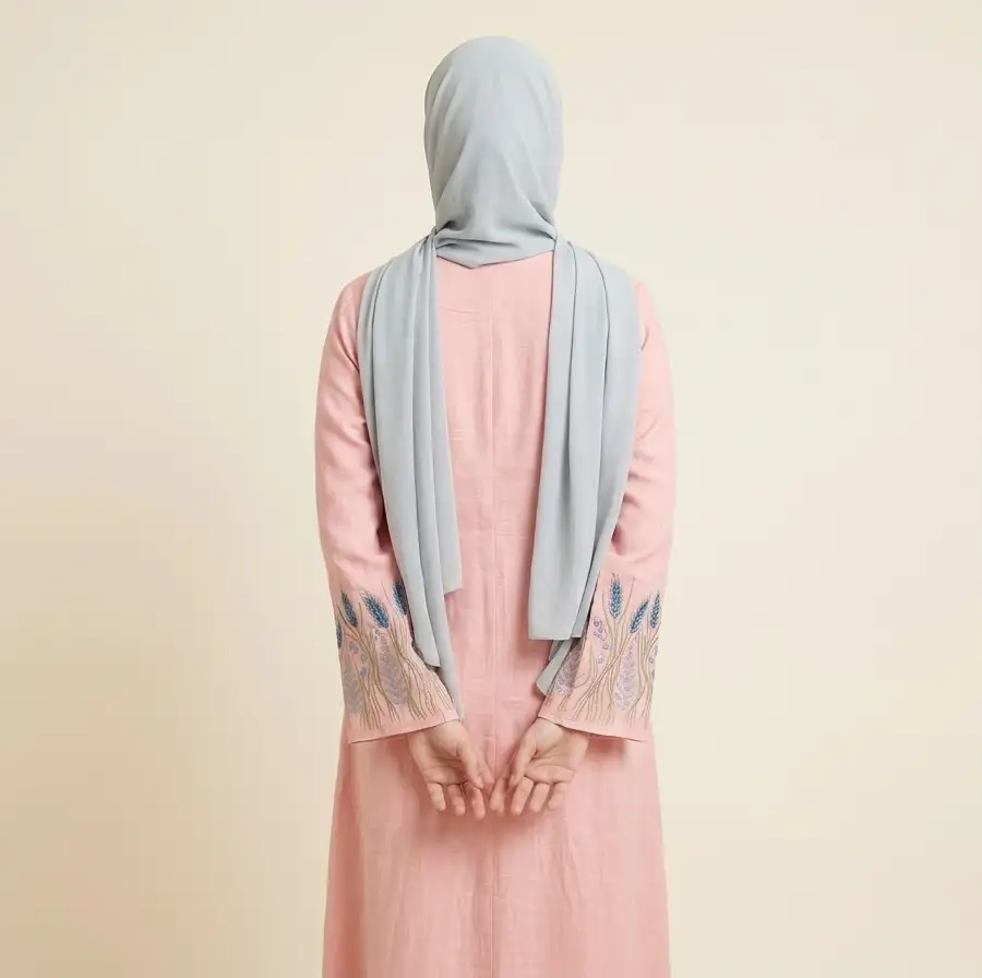 Full back view of a hijabi model wearing the pink linen-viscose maxi dress with detailed sleeve embroidery visible on both arms.