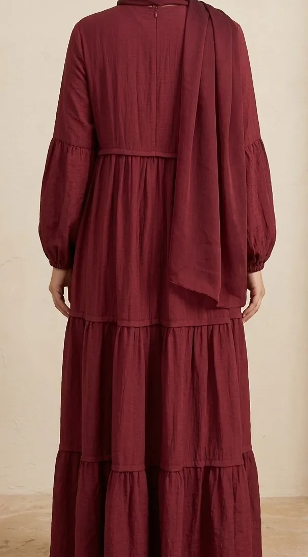 Back view of model wearing the burgundy red tiered maxi dress showing hidden back zip closure, flowing tiered seams, and full-coverage hijab drape.