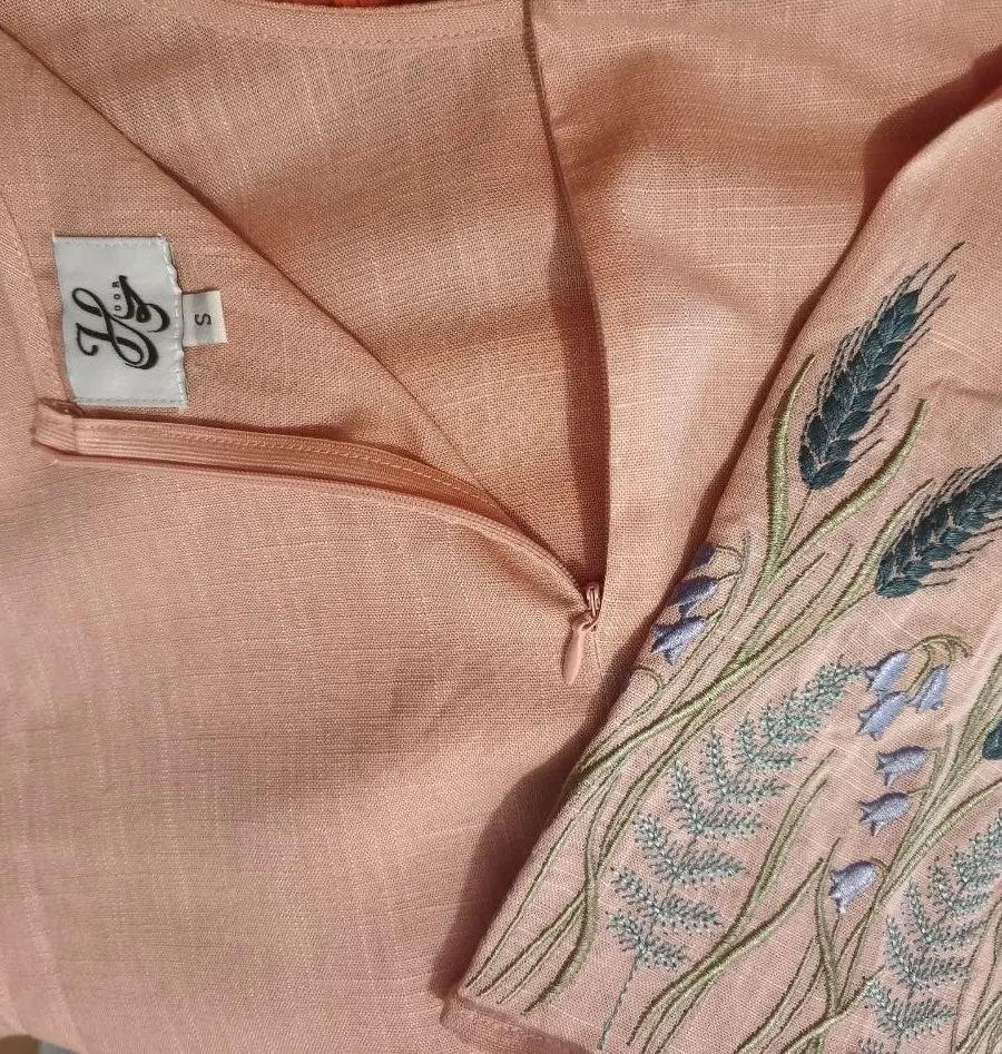 Detailed view of a pink linen-viscose dress styled with detailed embroidery along the bodice.
